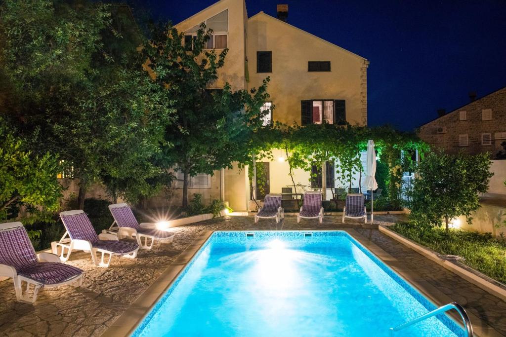默克斯卡罗扎公寓别墅的一个带椅子的游泳池,晚上有房子