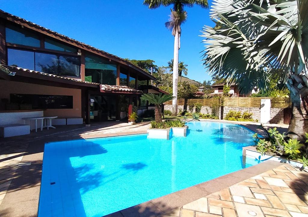 伊利亚贝拉Monalisa Guesthouse Pé na Areia Ilhabela的一座大蓝色游泳池,位于房子前