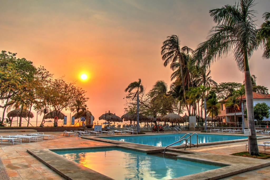 圣玛尔塔埃斯特拉圣塔玛酒店与会议中心的一座位于度假村的游泳池,享有日落美景