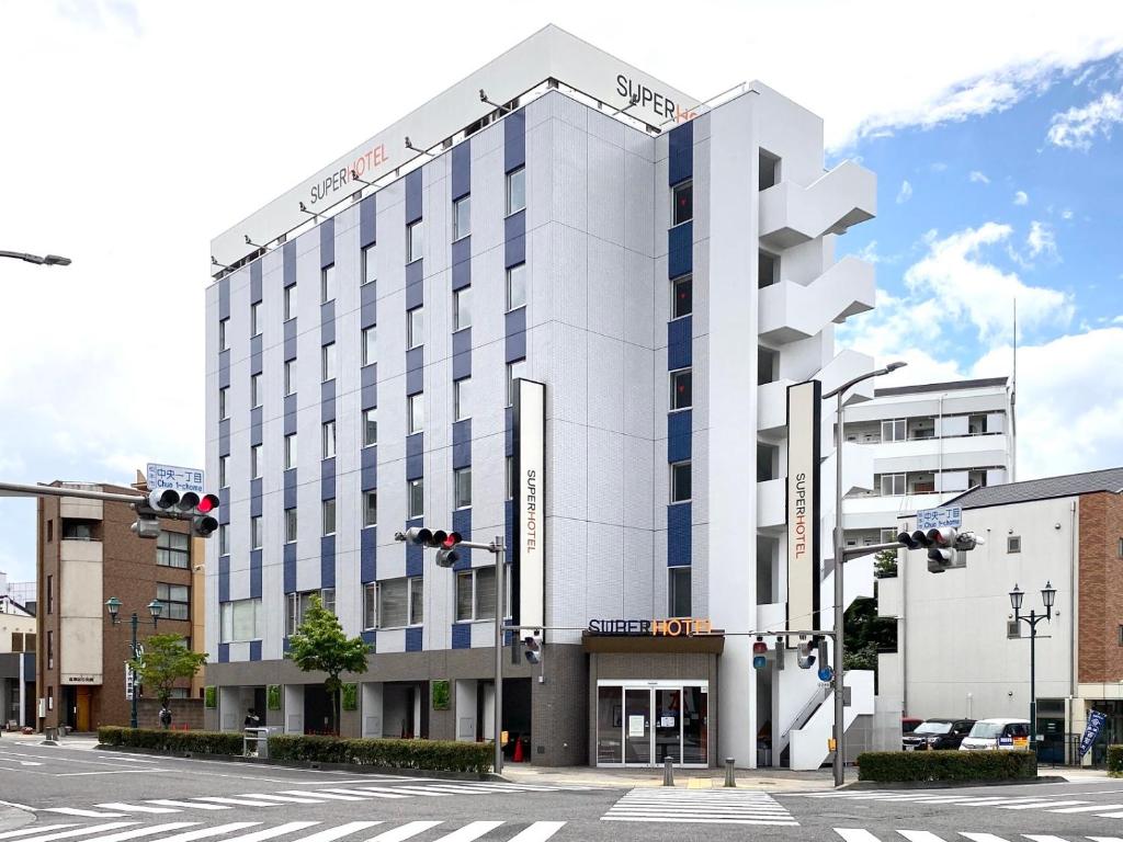 松本松本站前超级酒店的白色的建筑,在街上有蓝色的窗户