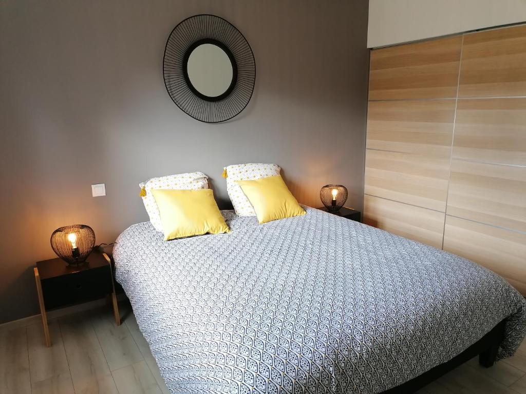 PlourhanLes gîtes aux portes de Saint-Quay-Portrieux的一间卧室配有一张带黄色枕头和镜子的床