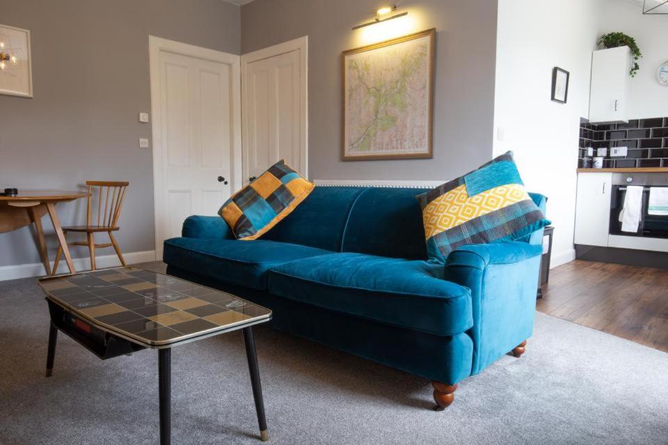 博特夫加滕High Terrace Apartment的客厅配有一张蓝色的沙发,配有一张桌子