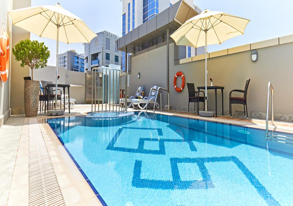 迪拜Rose Plaza Hotel Al Barsha的大楼内带遮阳伞的游泳池