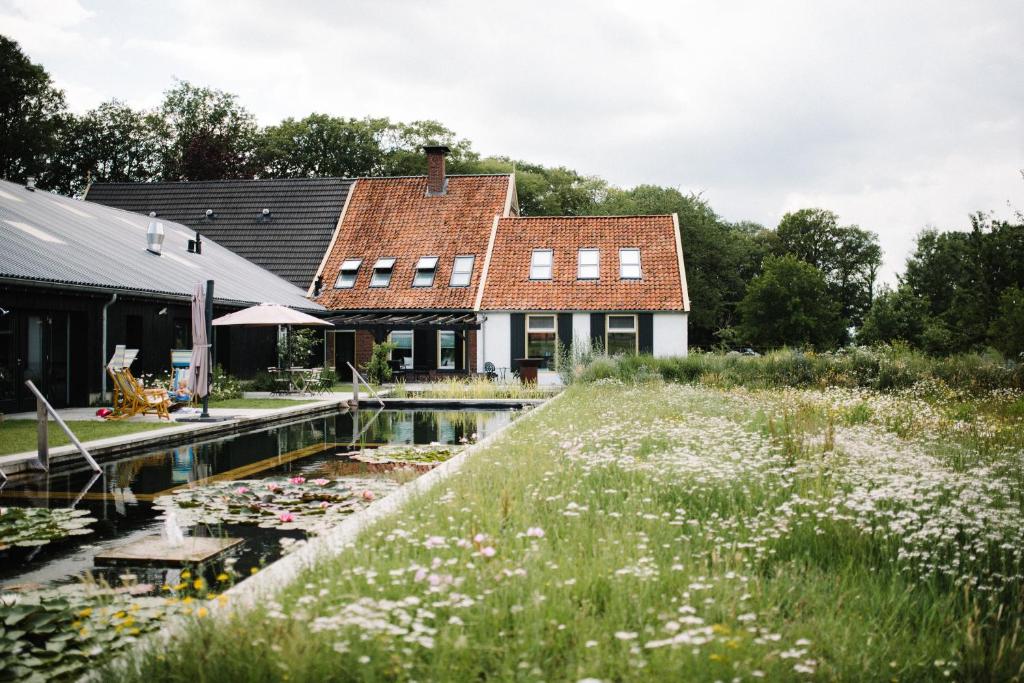 DiepenheimDe Woeste Wieven op Erve Bonkert的前面有池塘的房子