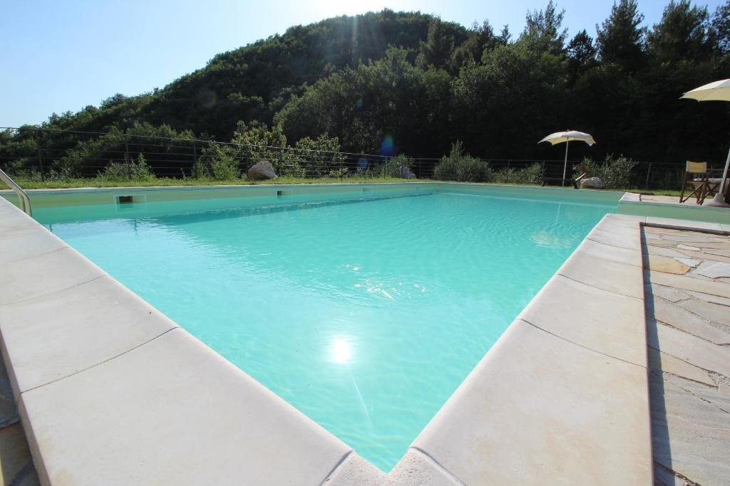 乌尔比诺laCelletta Country House的一个大蓝色游泳池,背景是一座山