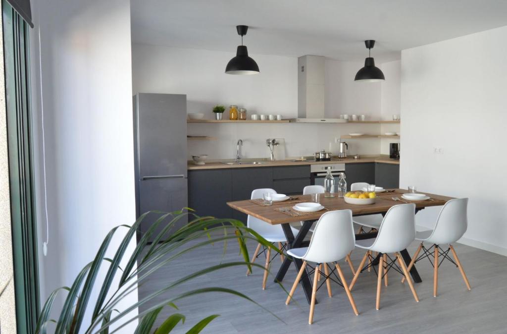 ArouOs Faros Pisos Turísticos的厨房以及带木桌和白色椅子的用餐室。