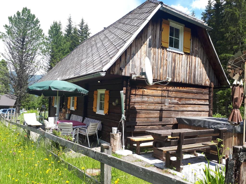 费拉赫Almhütte的小木屋配有野餐桌和雨伞