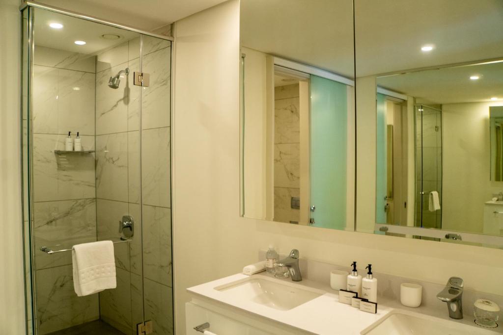 约翰内斯堡The Leonardo的浴室配有盥洗盆和带镜子的淋浴