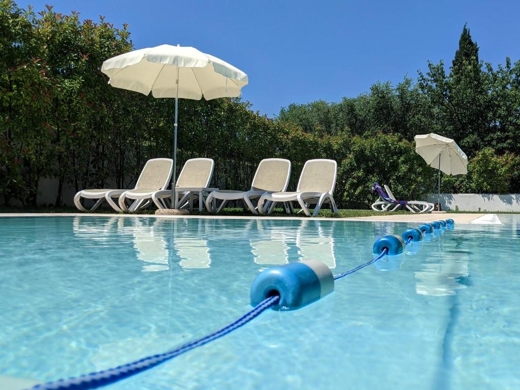 加尔达Residence Corte del Bosco的一个带椅子和遮阳伞的游泳池