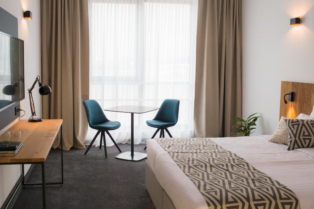 BrezovicaRoko Garni Hotel的酒店客房配有一张床、两把椅子和一张桌子