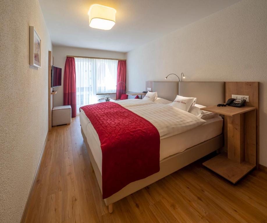 圣莫里茨Hotel Sonne St. Moritz 3* Superior的一间卧室配有一张带红色毯子的大床