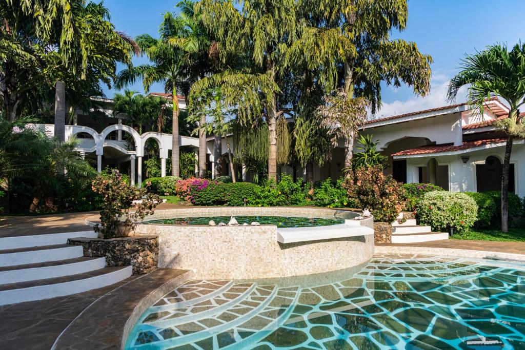 马林迪Hotel Villa Malindi的树木繁茂的庭院中的一个游泳池