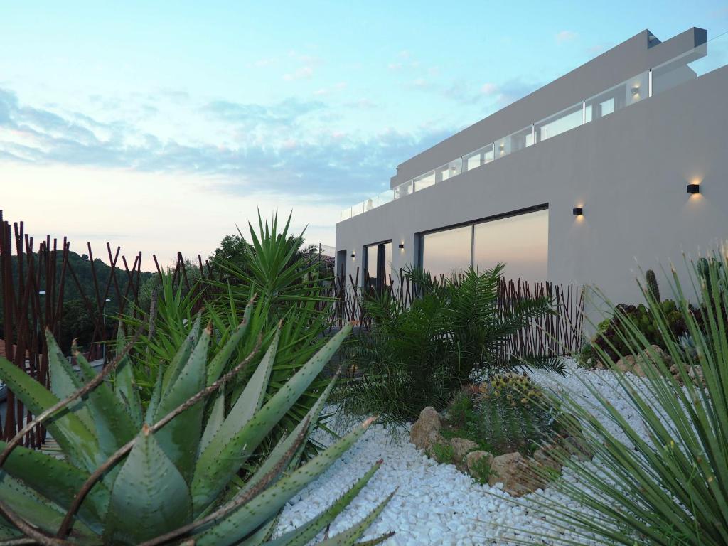 巴古尔Casa Lou, architect villa with heated pool at Begur, 470m2的前面有大量植物的房子