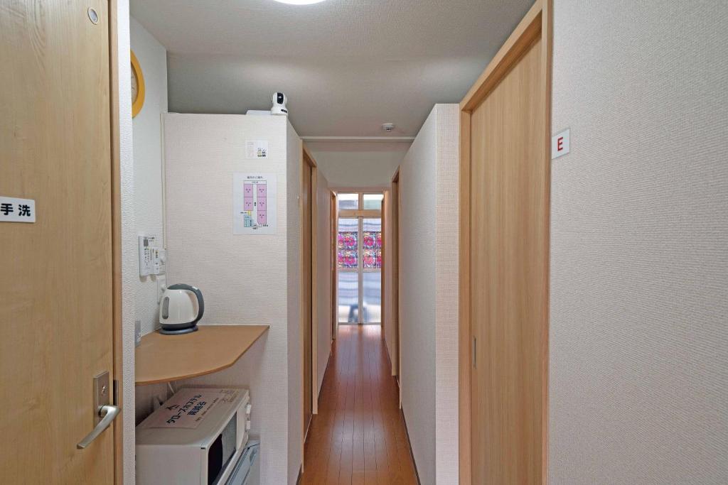 KoshigayaTaro's Hostel Minami Koshigaya的走廊通往带柜台和炉灶的厨房