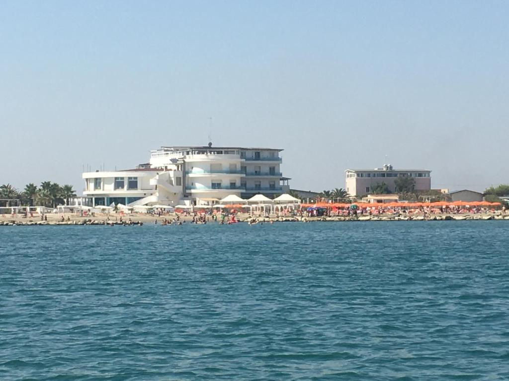 玛格丽塔萨沃亚Hotel Del Sole的海滩上设有遮阳伞和水面上的人物