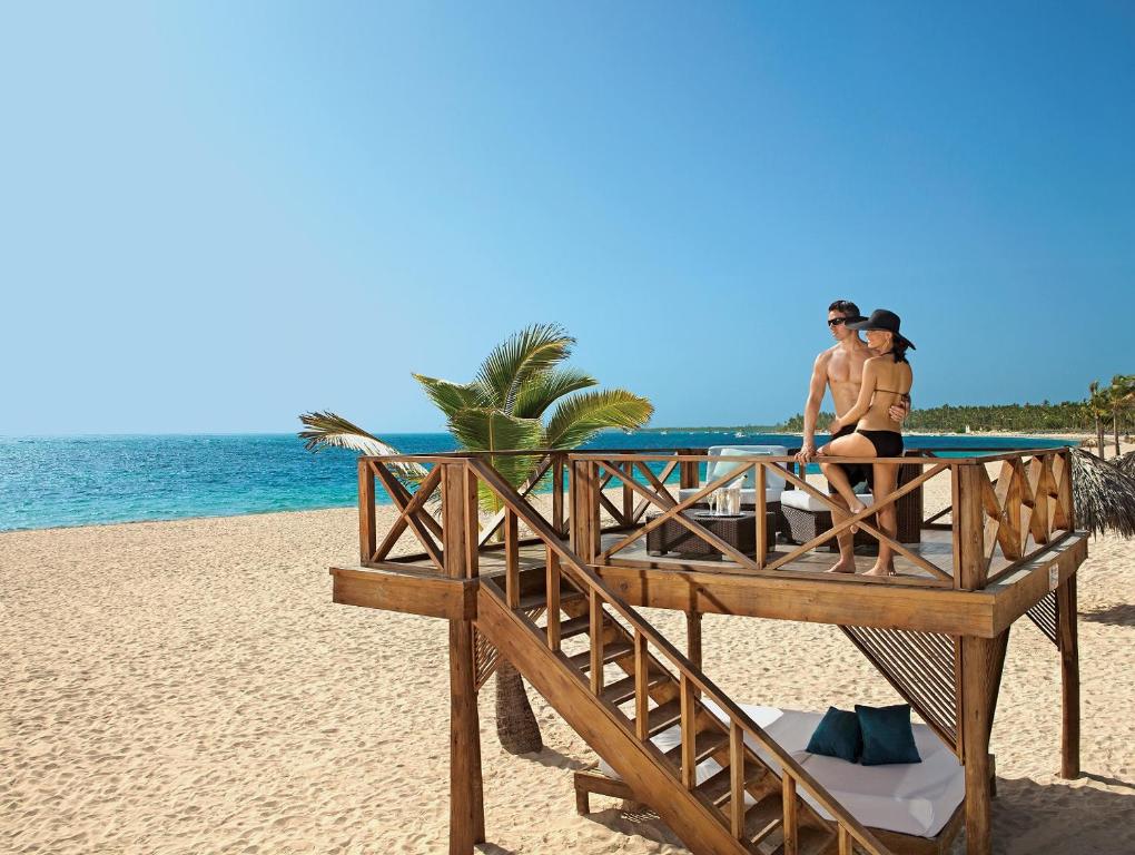 蓬塔卡纳Secrets Royal Beach Punta Cana - Adults Only - All Inclusive的两人坐在海滩上的码头