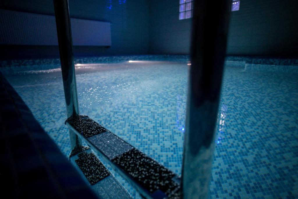 姆拉哥沃Hotel Rezydencja Mazury SPA & Lake的游泳池铺有蓝色瓷砖地板,水面