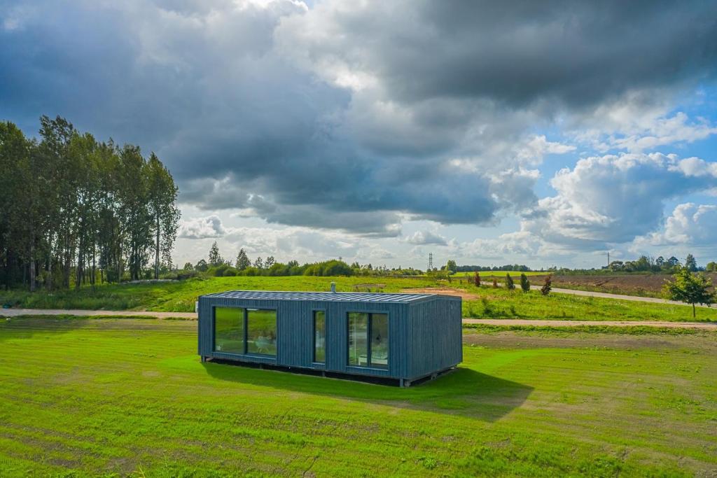 StragutėTAURO TROBA “The Ox Shelter”的绿色田野上的蓝色小房子