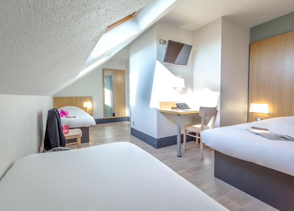 佩皮尼昂B&B HOTEL PERPIGNAN Nord Aéroport的酒店客房配有两张床和一张书桌
