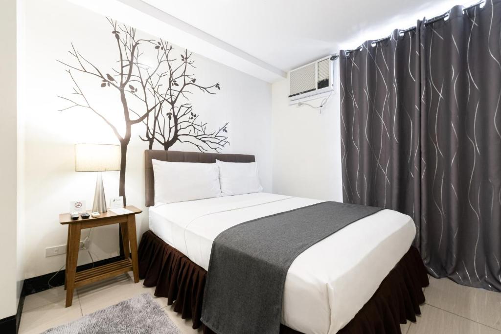 马尼拉马卡蒂阿蒂米斯广场酒店的一间卧室配有一张带黑色窗帘的床