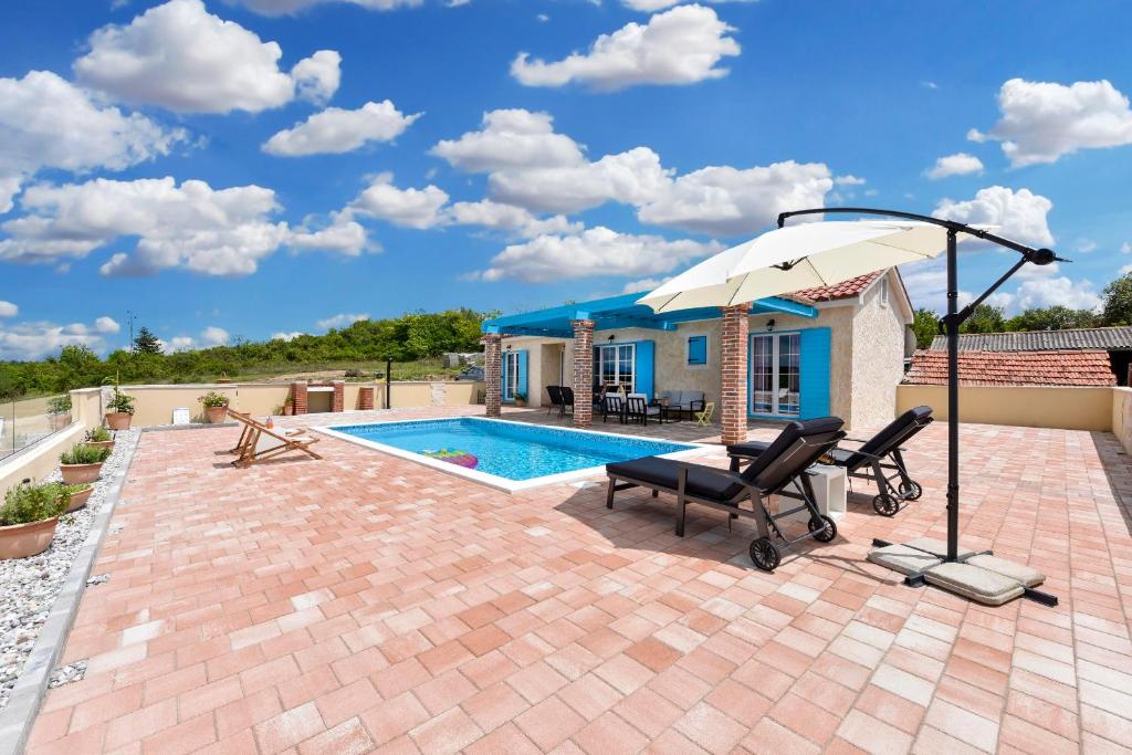 苏科尚Villa Jurenda的一个带两把椅子和一把遮阳伞的庭院,毗邻一个游泳池