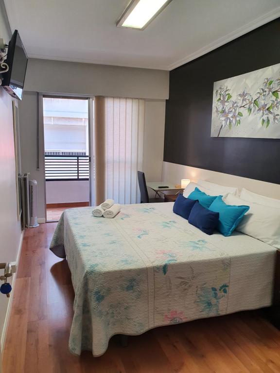 洛格罗尼奥Pensión El Espolón的一间卧室配有一张带蓝色枕头的大床