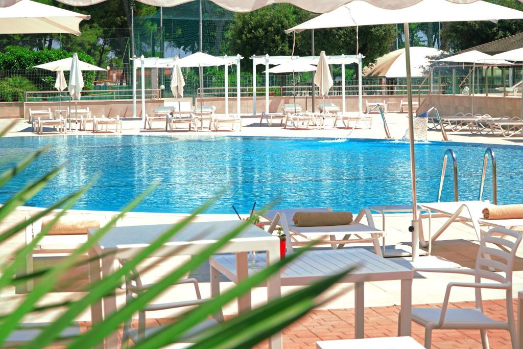 塔兰托图尔斯波特酒店的一个带椅子和遮阳伞的大型游泳池