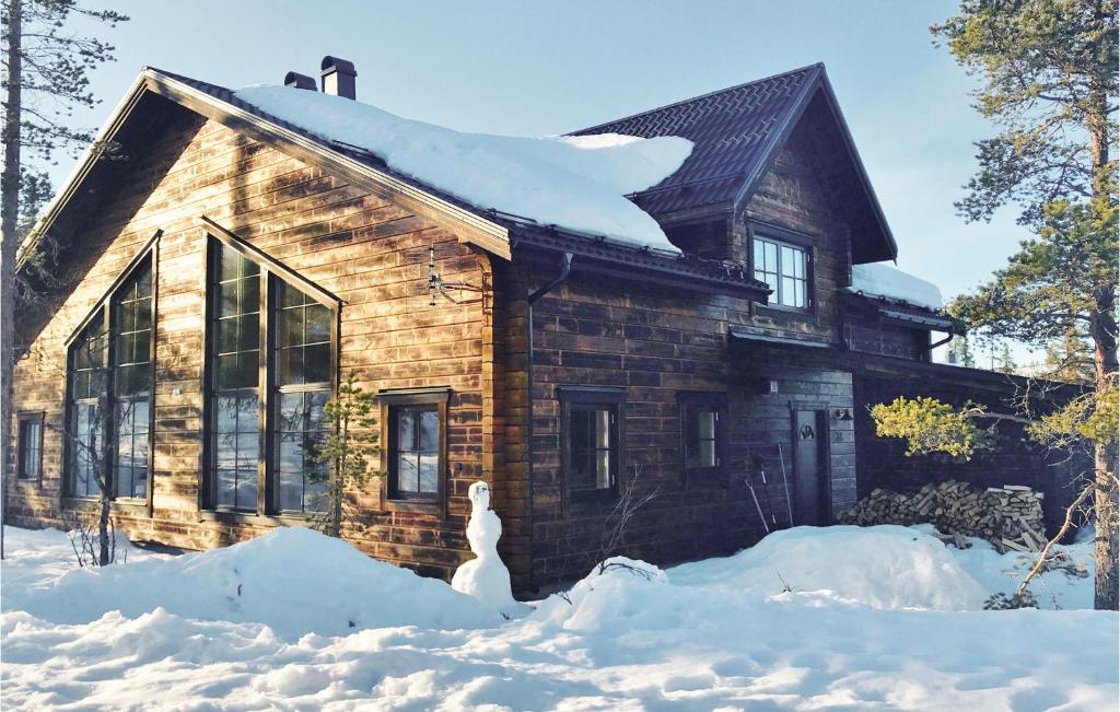 韦姆达伦Gorgeous Home In Vemdalen With Sauna的雪地里的小木屋,前面有一位雪人