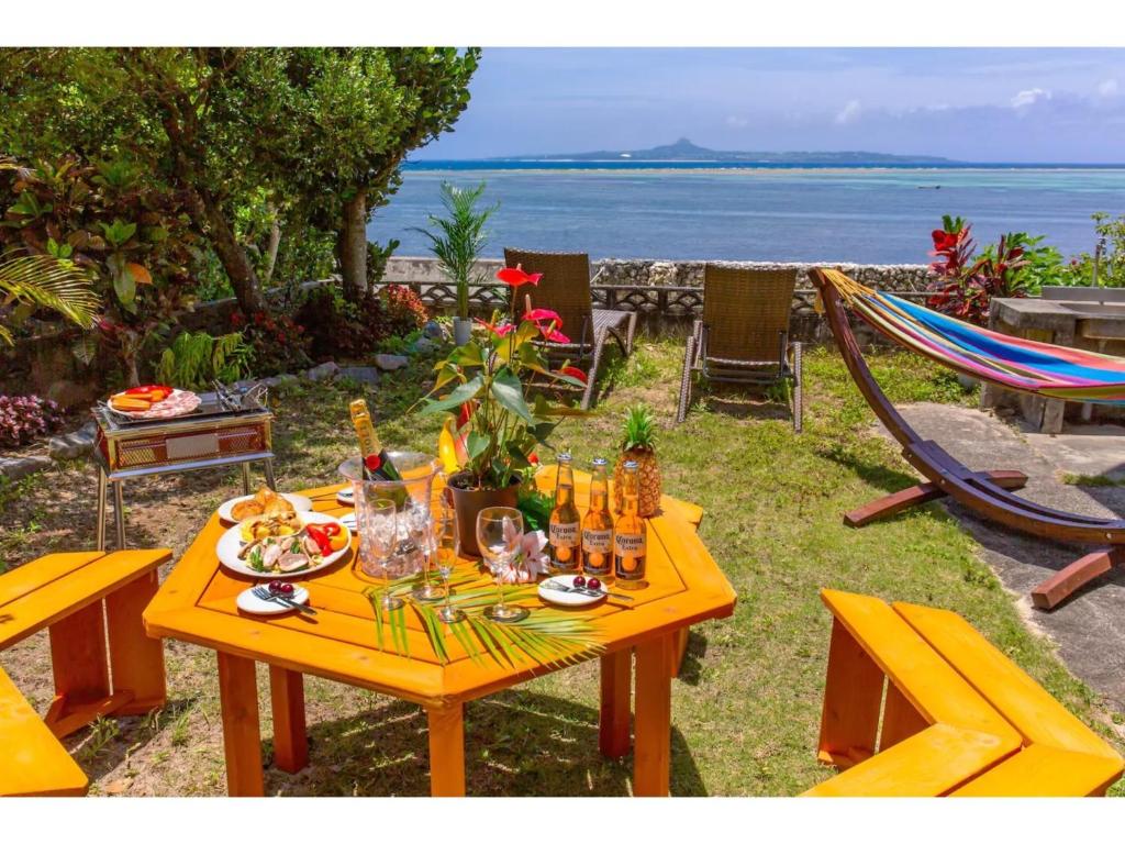 备濑Ojii no Ie - Vacation STAY 84243的一张黄色桌子,上面有食物和饮料,在海边