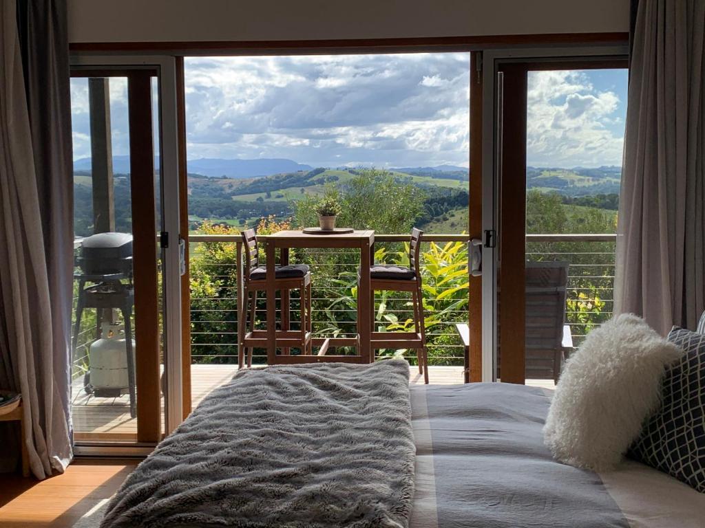 班加洛Callemondah Studio with stunning views, in Bangalow and Byron Hinterland的一间卧室设有一张床和一个美景阳台