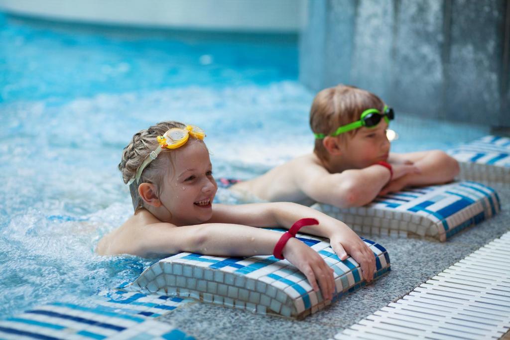 塔林塔林快捷酒店的两个小孩在背上护目镜的游泳池游泳