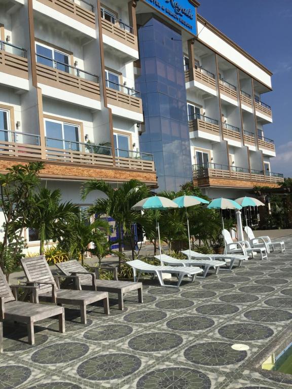圣胡安EM Royalle Hotel & Beach Resort的建筑物前的一排椅子和遮阳伞