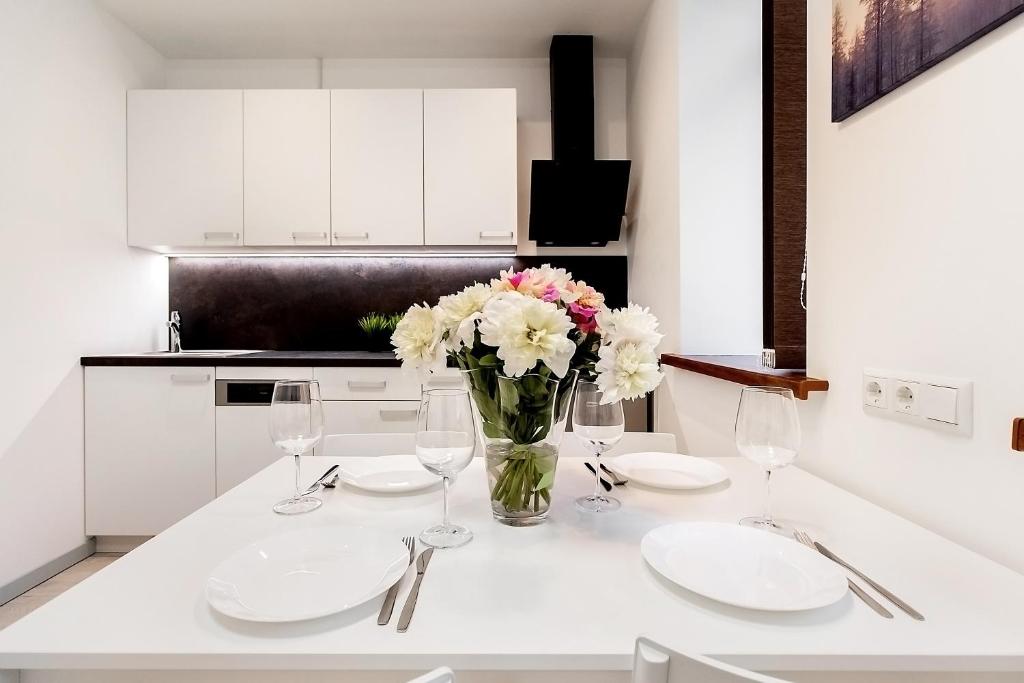 尤尔马拉Apartments Daina的白色的厨房,桌子上放着花瓶