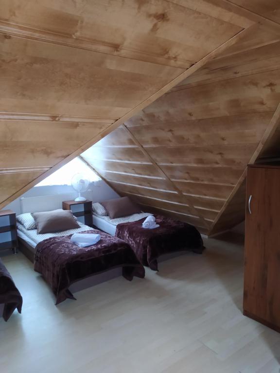 韦巴Pokoje gościnne LUSIA的阁楼间设有两张床和木制天花板