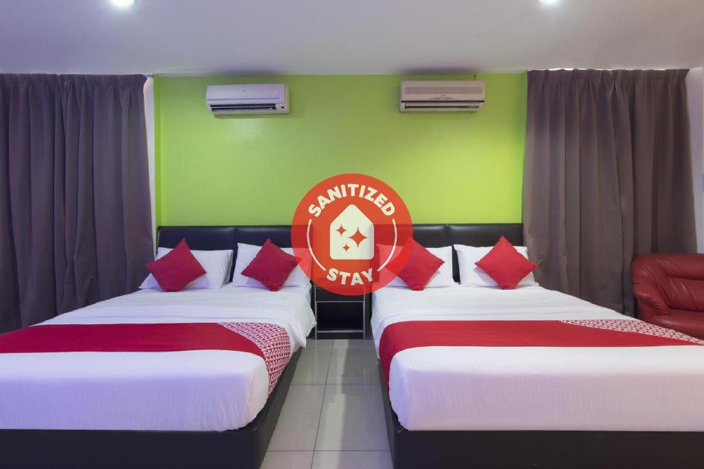 汝来OYO 44072 Mines Cempaka Hotel的绿色和红色客房的两张床