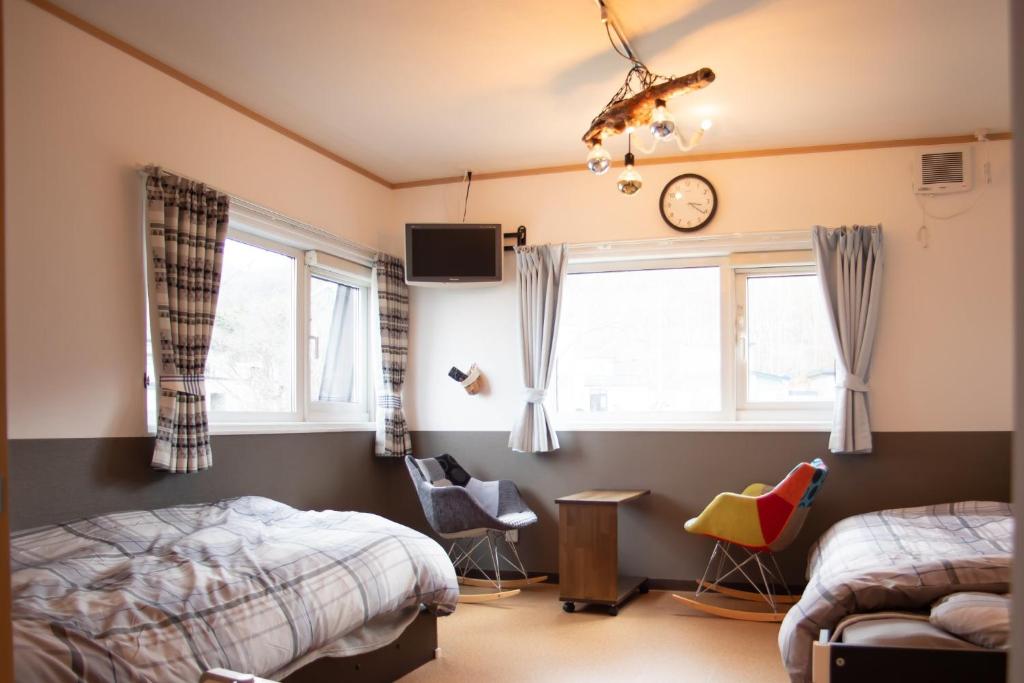 小樽Otaru Village - Vacation STAY 84257的一间卧室设有两张床,墙上挂着一个时钟。