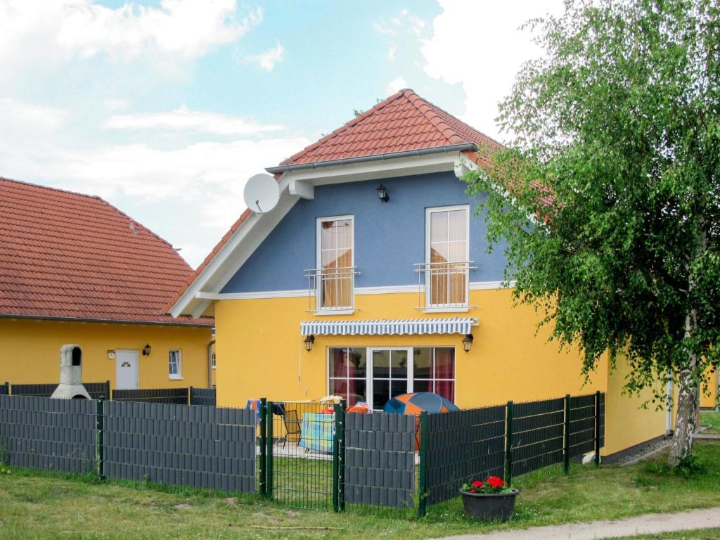 VerchenHoliday Home Ferienpark Verchen-3 by Interhome的黄色和蓝色的房子,有黑色的栅栏