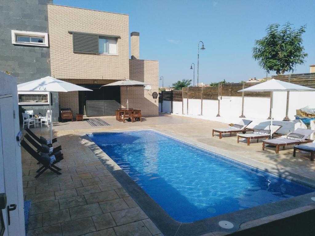 科马鲁加Casa Can Miras的房屋旁的游泳池配有椅子和遮阳伞