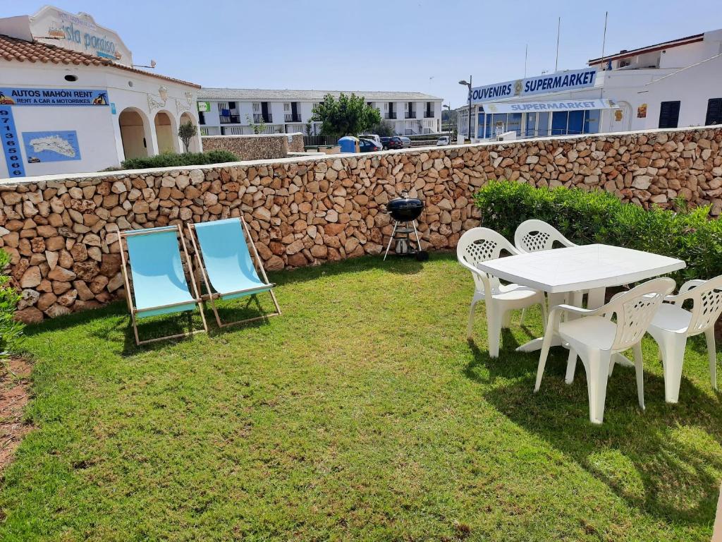 阿雷纳尔登卡斯特尔Apartamento en Arenal a 5 minutos de la playa的石墙旁的院子内的桌椅