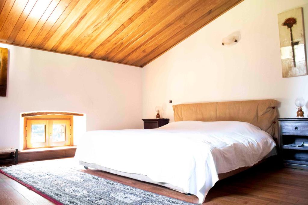 Piazza al SerchioGARFAGNANA spazioso appartamento, relax! prenotaz min 3 giorni的卧室设有白色的床和木制天花板。