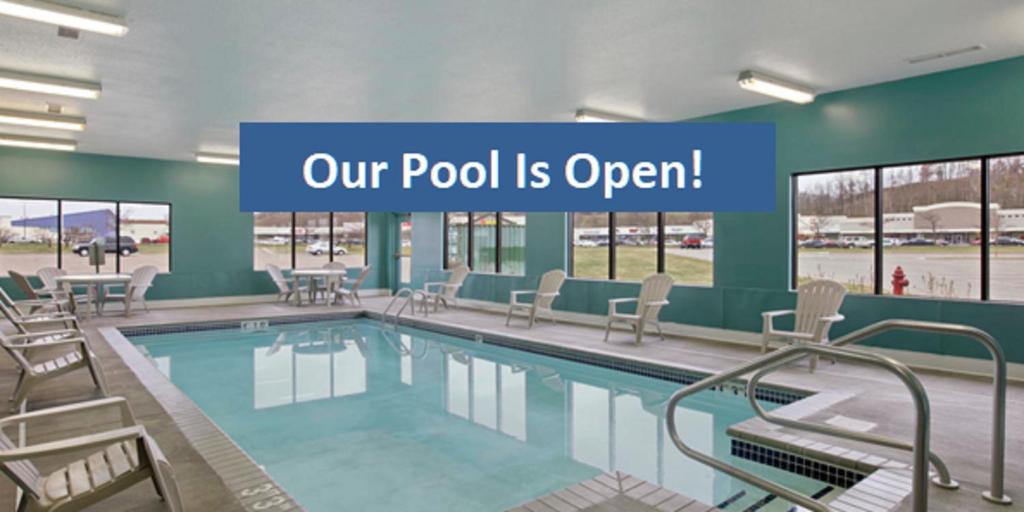 欧克莱尔欧克莱尔贝蒙特旅馆套房酒店的游泳池配有椅子和阅读游泳池的标志,开放