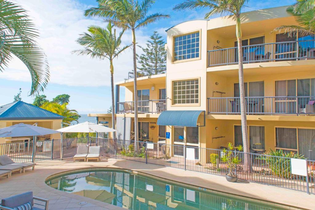 麦夸里港海滨假日公寓的一个带游泳池和棕榈树的度假村