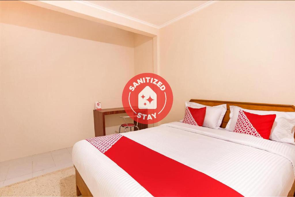 巴东OYO 3252 Lansano Residence Syariah的一间卧室配有一张带红白毯子的床
