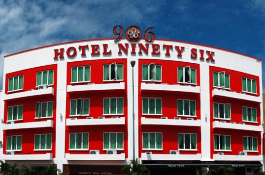 马六甲906 Hotel Melaka Raya的一座红色的酒店,在96座大楼的顶部设有钟