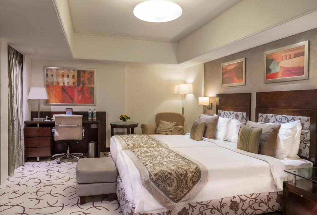 艾哈迈达巴德财富公园艾哈迈达巴德酒店的酒店客房设有一张大床和一张书桌。