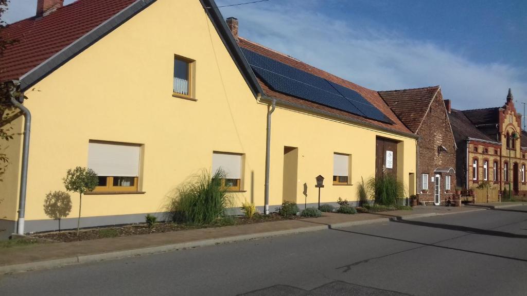 DrahnsdorfFerienwohnung Wildau-Wentdorf的街道上一座黄色建筑,上面有太阳能电池板
