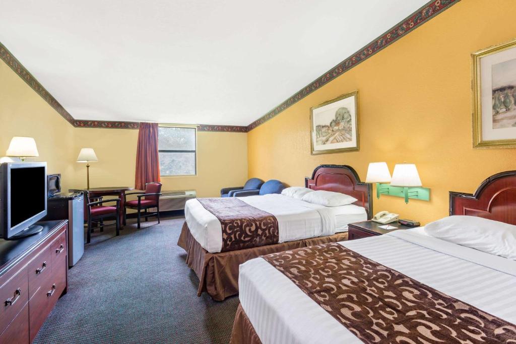 湖城Howard Johnson by Wyndham Lake City的酒店客房设有两张床和一台平面电视。