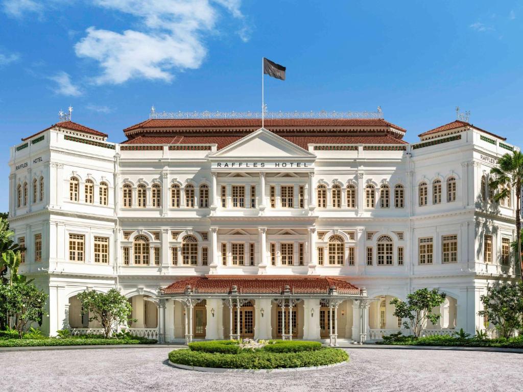 新加坡新加坡莱佛士酒店的一座白色的大建筑,上面有旗帜