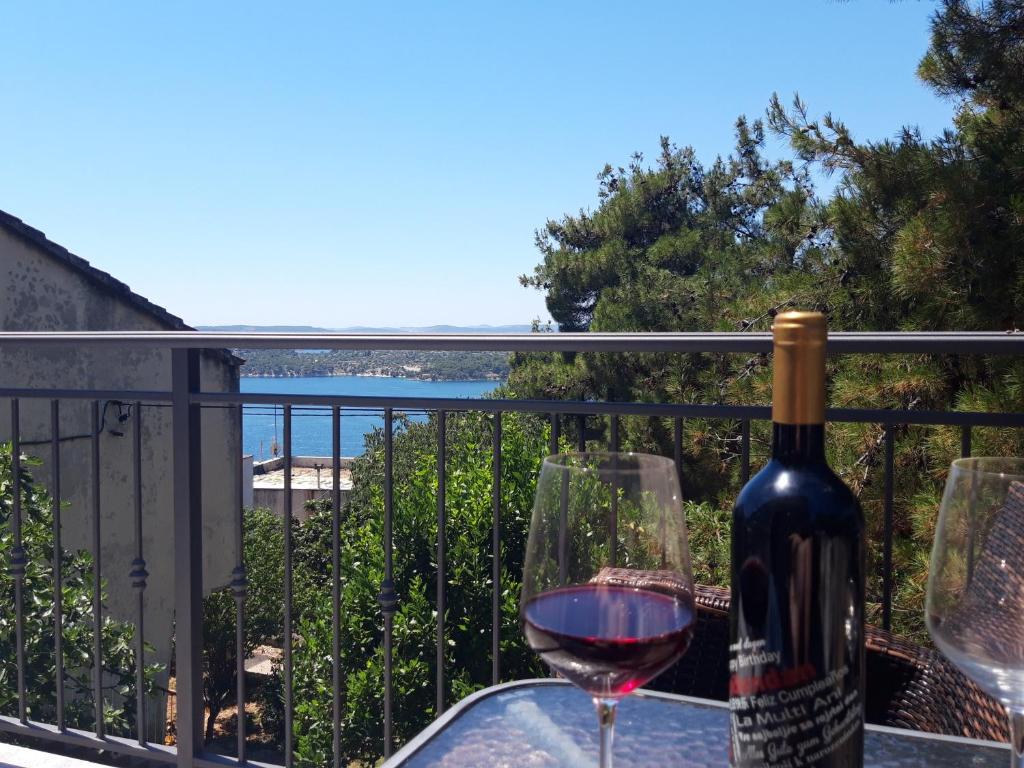 希贝尼克Apartmani Ponistra的阳台上的一瓶葡萄酒和两杯酒