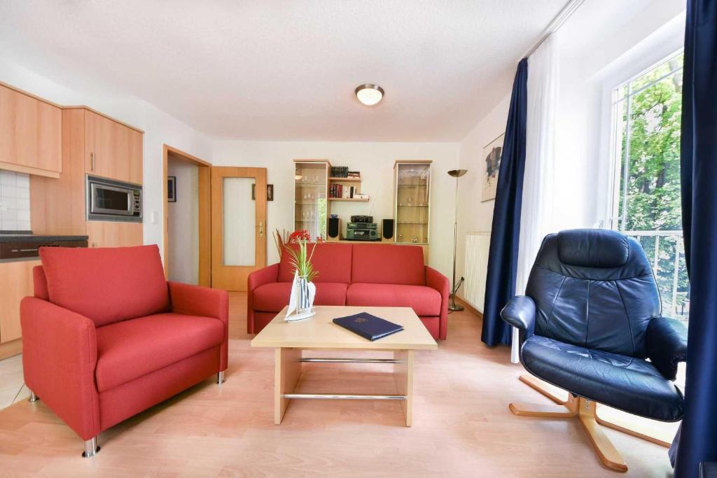 赛巴特班森Haus Strandoase 23的客厅配有2把红色椅子和桌子